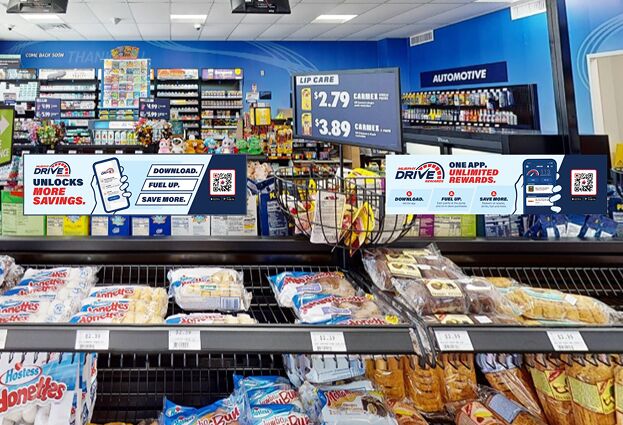 A convenience store retail shelf filled with packaged Hostess Donettes and baked goods, with Murphy Drive Rewards digital advertisements visible above the rack in front of the checkout counter.