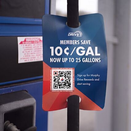 A close-up of a promotional tag hanging on a black gas pump hose, advertising 'MEMBERS SAVE 10¢/GAL NOW UP TO 25 GALLONS' with a QR code for Murphy Drive Rewards.