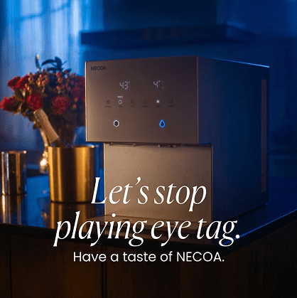 A sleek, modern NECOA brand water dispenser sits on a kitchen countertop in a dimly lit, atmospheric room. In the background, there is a golden champagne bucket with a bottle and a bouquet of red roses. Overlay text in the foreground reads 'Let's stop playing eye tag. Have a taste of NECOA.'