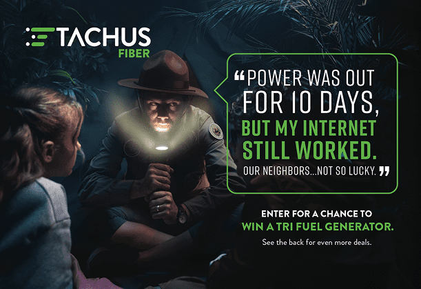 A man wearing a park ranger hat shines a flashlight on his face while sitting in the dark with a young girl, telling her how his internet still worked during a 10-day power outage. The Tachus Fiber logo is visible in the upper left corner, and text promotes a chance to win a tri-fuel generator.