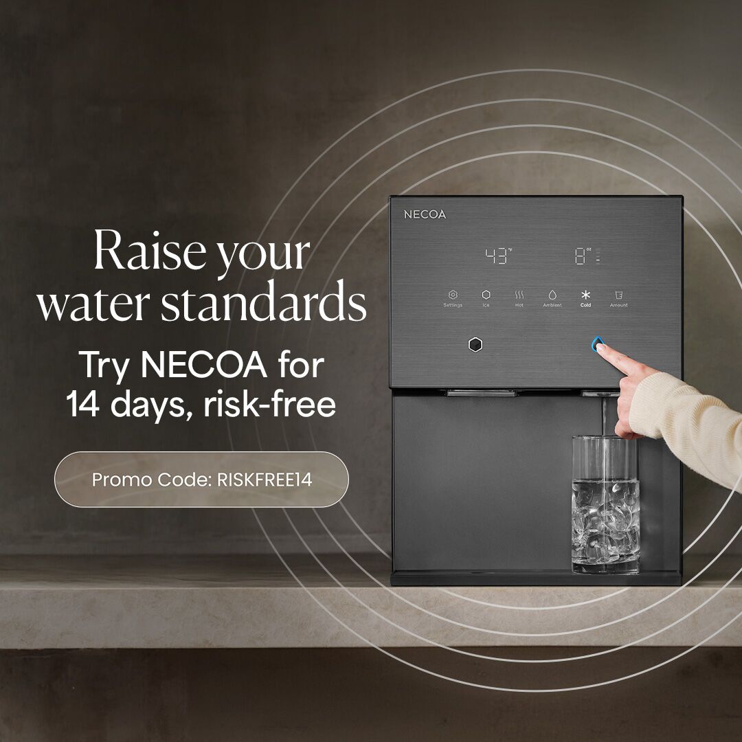 A sleek, dark grey NECOA countertop water dispenser being used to fill a glass of ice. On the left, promotional text reads, 'Raise your water standards. Try NECOA for 14 days, risk-free' with a button containing the promo code 'RISKFREE14'.