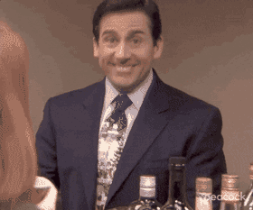 A looping clip of Michael Scott from The Office smiling awkwardly and nodding while looking towards someone, wearing a navy suit and patterned tie behind a bar with bottles.